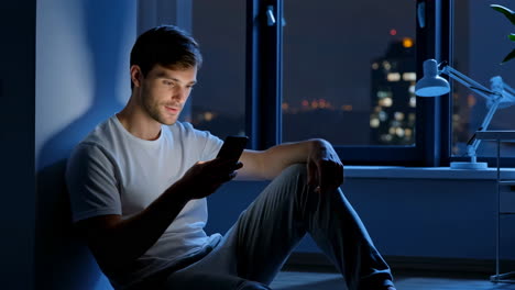 young man using smartphone in a dark room at night