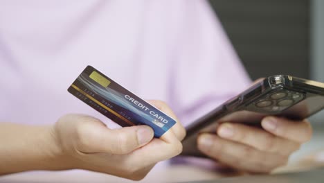 una mujer está usando una tarjeta de crédito para pagar compras en línea en una aplicación móvil por teléfono inteligente.