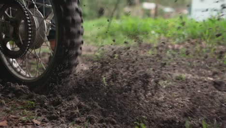 a dirt bike rider kicking up dirt while driving past