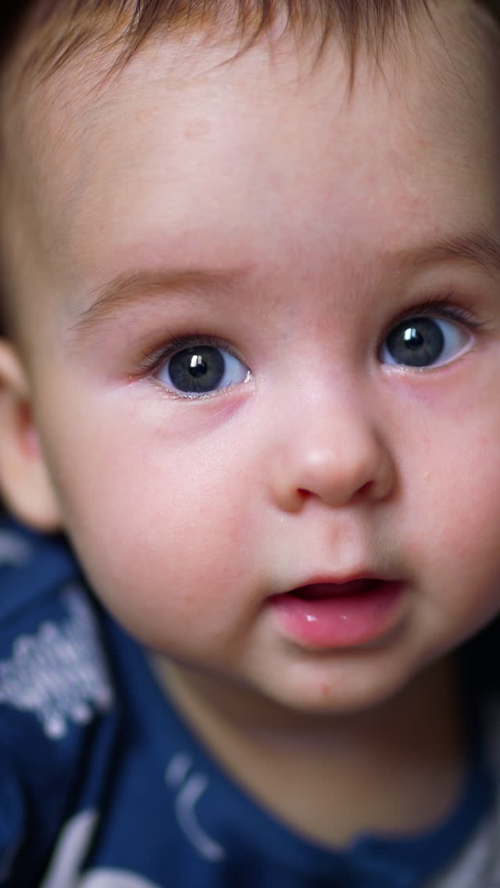 Adorable smile from a beautiful Caucasian kid lying on his belly. Close up. Blurred background. Vertical video