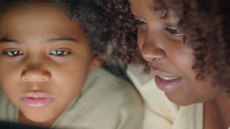 black woman and little son using tablet in night
