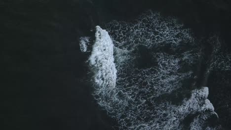 straight down aerial as whitewater ocean waves crash onto dark water