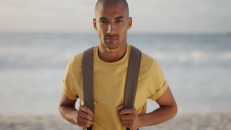 portrait of young hispanic man looking at camera serious on calm summer beach seaside