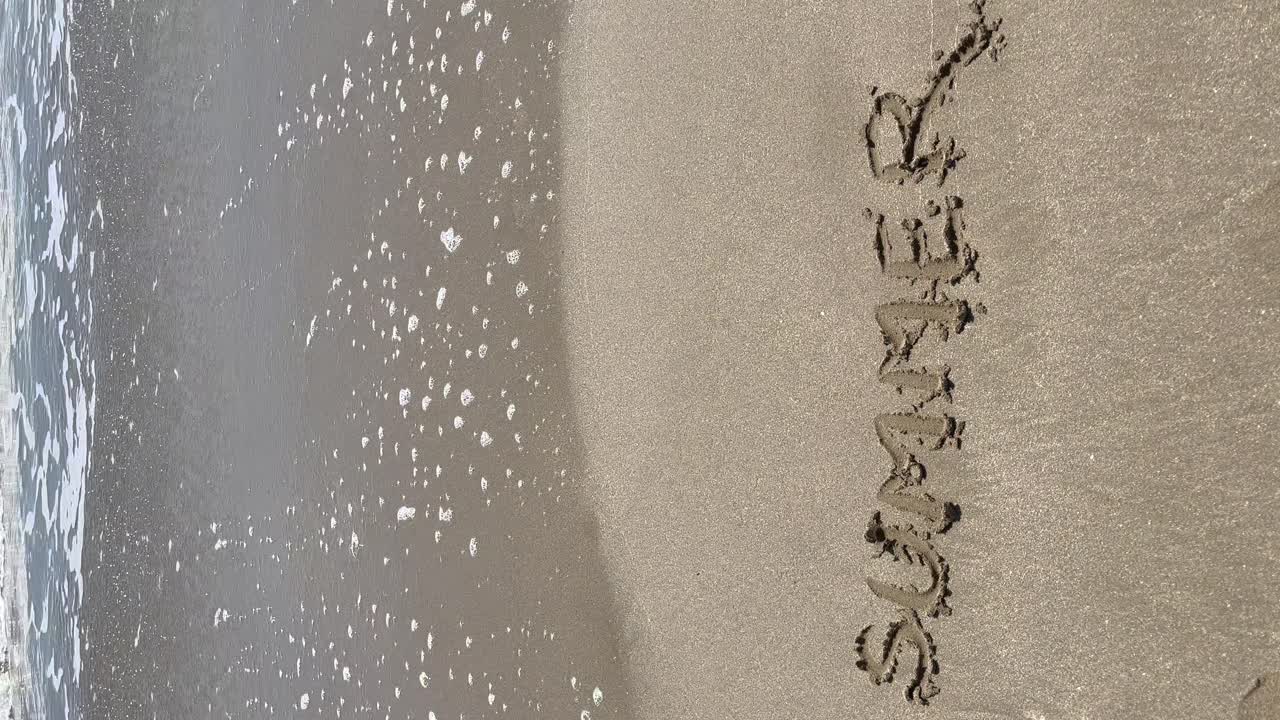 모래 에 쓰여진 "여름"이라는 단어 의 수직적 인 모습 과 배경 에 있는 바다 의 파도