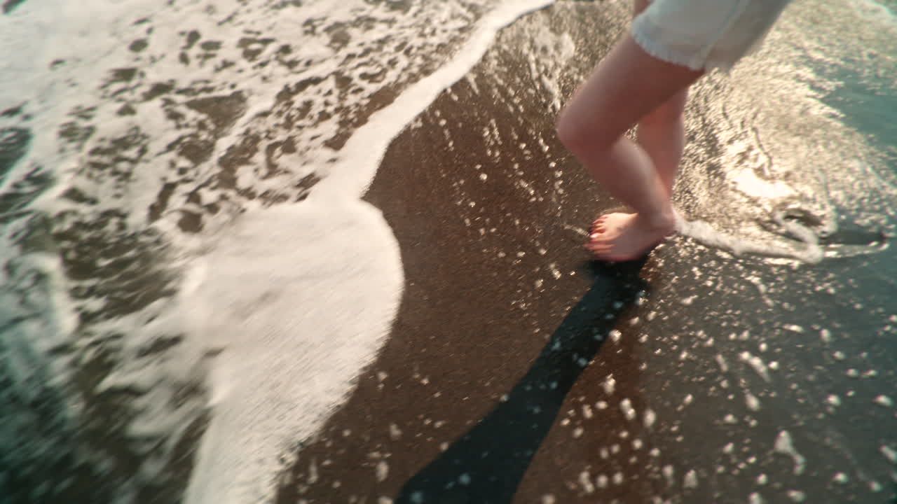 Person standing on the beach with waves washing over their feet