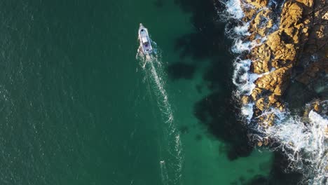 un barco pesquero que busca bancos de salmonetes alrededor de un promontorio costero escarpado.