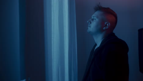 man looking out of a window at night