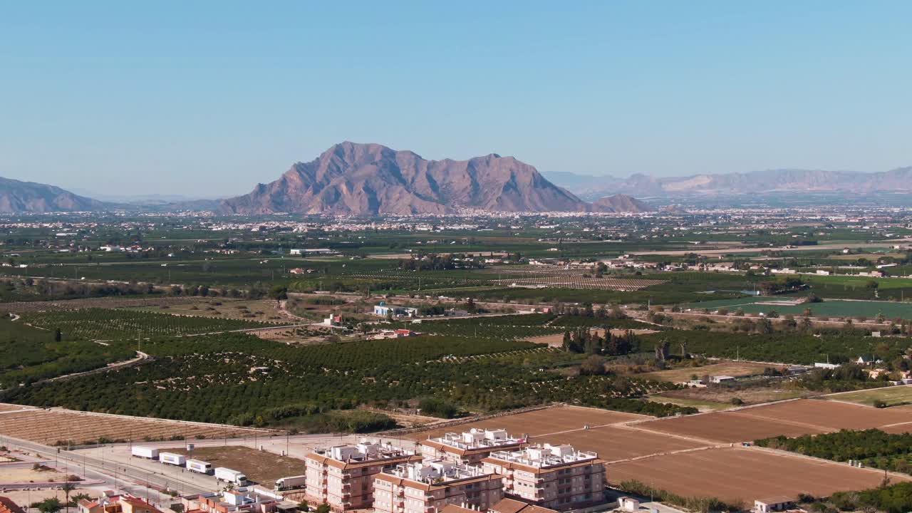 スペインのアルゴルファ近郊にある建物、緑豊かな柑橘農園の畑、そして地中海の山岳風景
