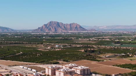 edificios, campos de cultivo de cítricos verdes y paisaje montañoso mediterráneo cerca de algorfa, españa