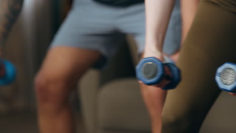 Fit-couple-training-dumbbells-indoors-close-up.-Man-with-woman-making-exercises.