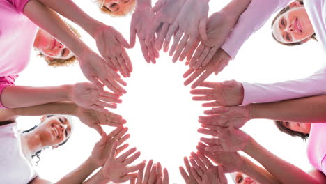 diverse group of smiling women touching hands outdoors in the sun