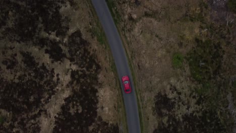 top down view of red car being driven round a bend of single track road