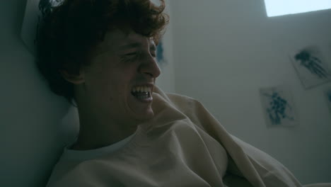 restrained patient laughing hysterically on bed in psychiatric hospital