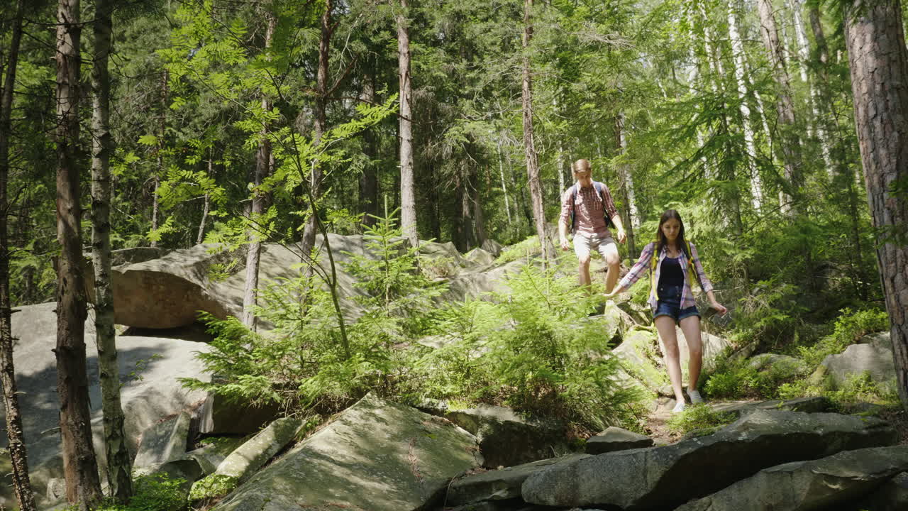 un par de turistas con mochilas van por un pintoresco camino de montaña
