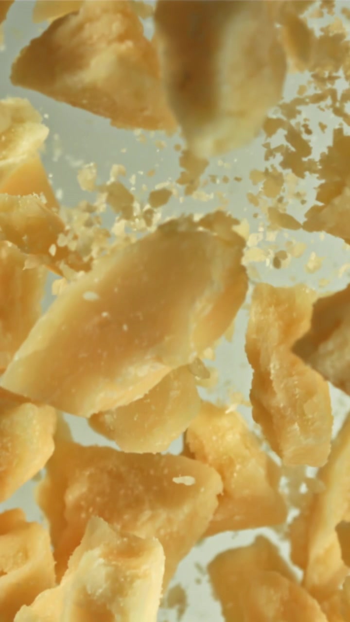 Primo piano al rallentatore di pezzi di Parmigiano che cadono