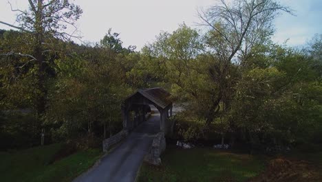 Luftdrohne-Zieht-Während-Des-Herbstes-Im-Land-Eine-Aufnahme-Einer-überdachten-Holzbrücke-Zurück