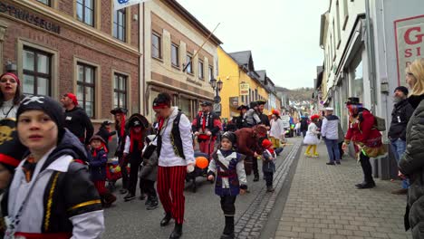 costumed german women dancing with kids on street parade of rose monday carnival, germany