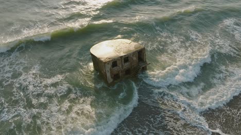 beautiful aerial establishing view of karosta concrete coast fortification ruins, sunny summer evening, golden hour light, stormy waves at baltic sea, slow motion birdseye drone orbit shot