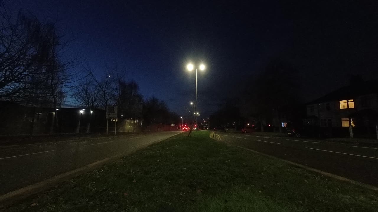 faros de vehículos de cercanías temprano en la mañana que pasan a ambos lados de la autopista británica, lapso de tiempo