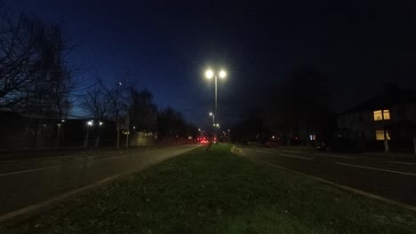 faros de vehículos de cercanías temprano en la mañana que pasan a ambos lados de la autopista británica, lapso de tiempo