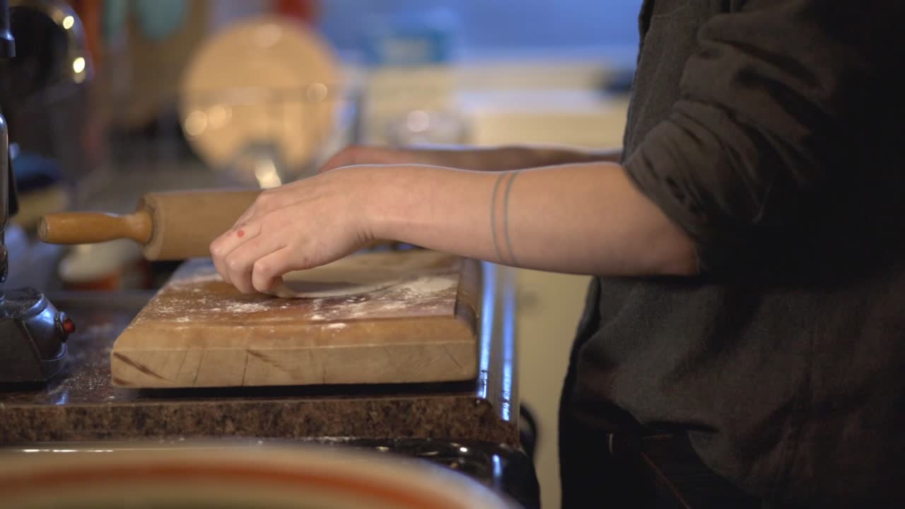 Side View Of A Baker Hand's Using Rolling Pin To Flatten The Dough On The Wooden Board - Slow Motion Shot