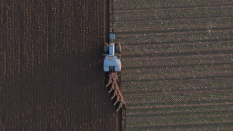 Aerial-view-of-a-farm-tractor-ploughing-a-field-in-Aberdeenshire-on-a-sunny-day,-Scotland