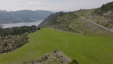 drone shot flying over green fields and farmland in mountains of norway