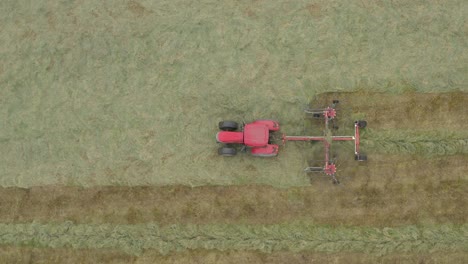 antena de un tractor rojo con rastrillo circular, moviéndose de derecha a izquierda en el marco
