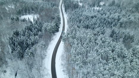 aerial pan shot showing cars driving on scenic winter road during beautiful snowy day with snow and ice