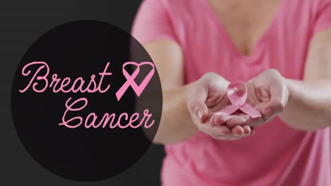 animation of breast cancer text over caucasian woman with pink ribbon on black background