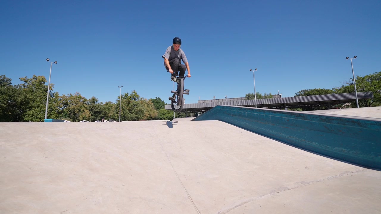 Giovane uomo su una BMX che esegue un salto in uno skatepark