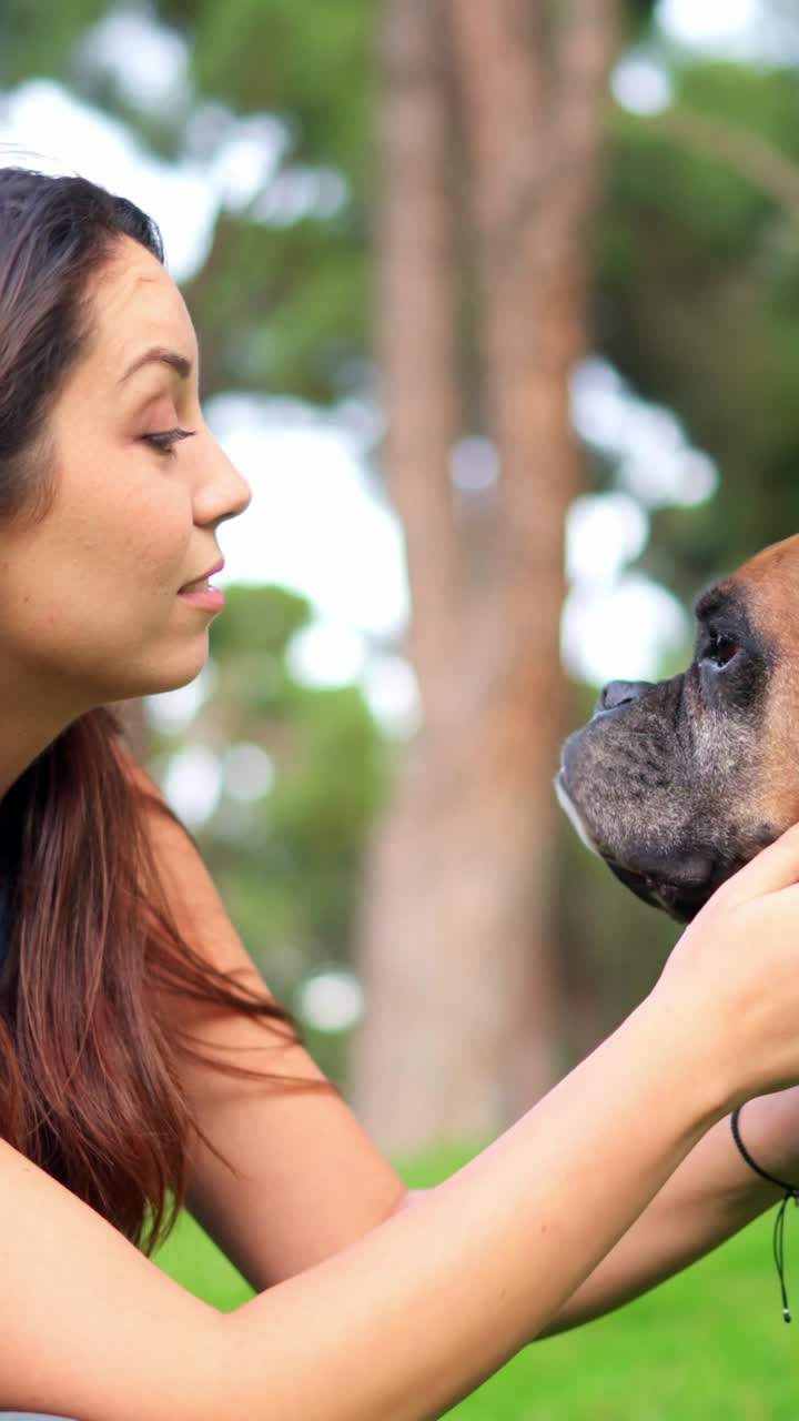 Jovem mulher carinhosamente com seu cão Boxer em um parque