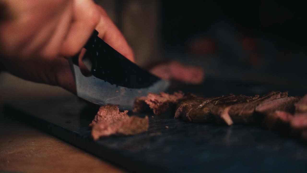 따뜻하고 시골적 인 조명 에서 절단 보드 에 매운 요리 된 고기 를 잘라내는 사람