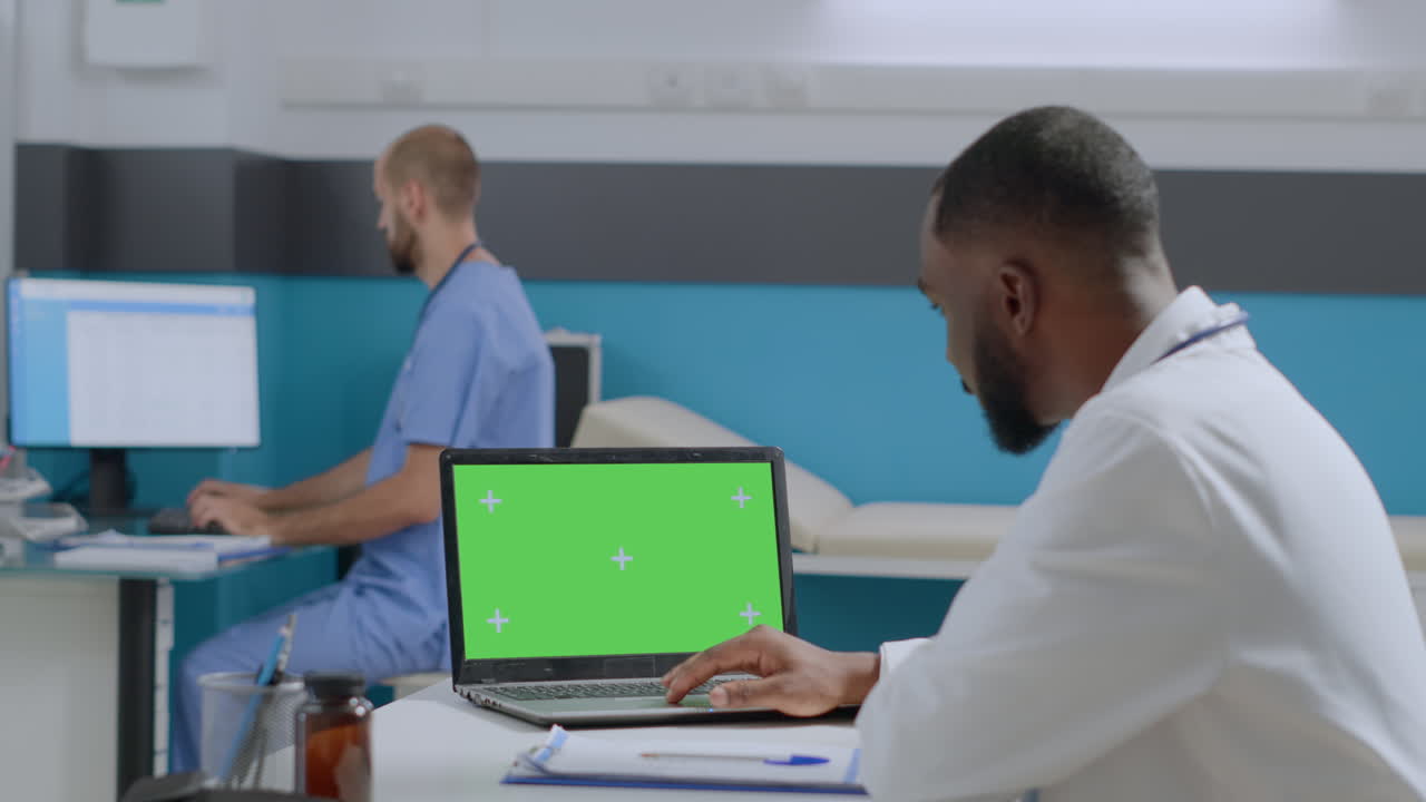 Doctor using laptop with green screen in clinic