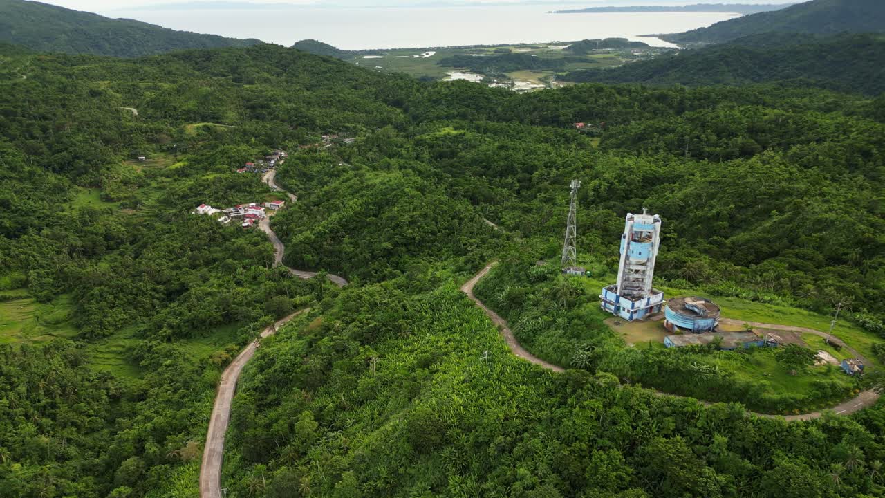 Aerial forward shot of Doppler weather radar station atop lush tropical mountains overlooking province Catanduanes, Philippines