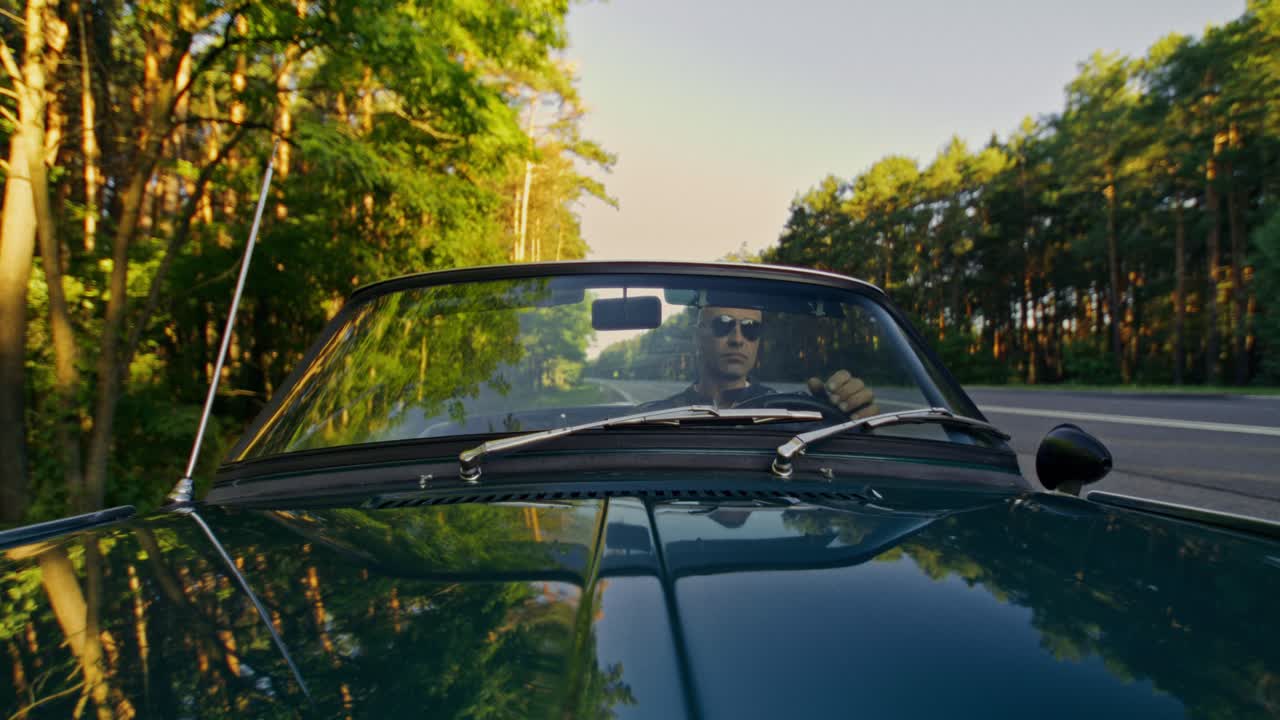 Man driving a convertible on a scenic road