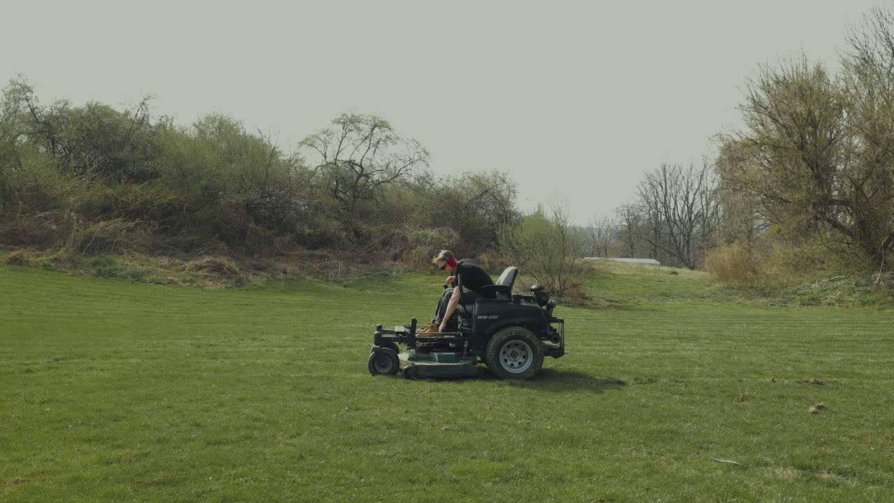 A man rides a lawnmower, stops, and switches it off. Ideal for lawn care, gardening, and outdoor lifestyle visuals