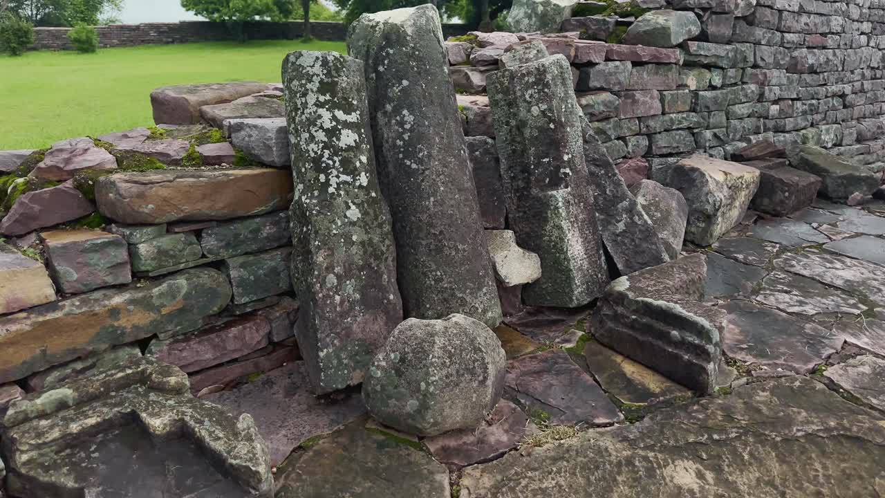 An ancient stone ruins with weathered blocks and moss, captured using a smooth panning camera movement, showcasing historic architecture and natural textures