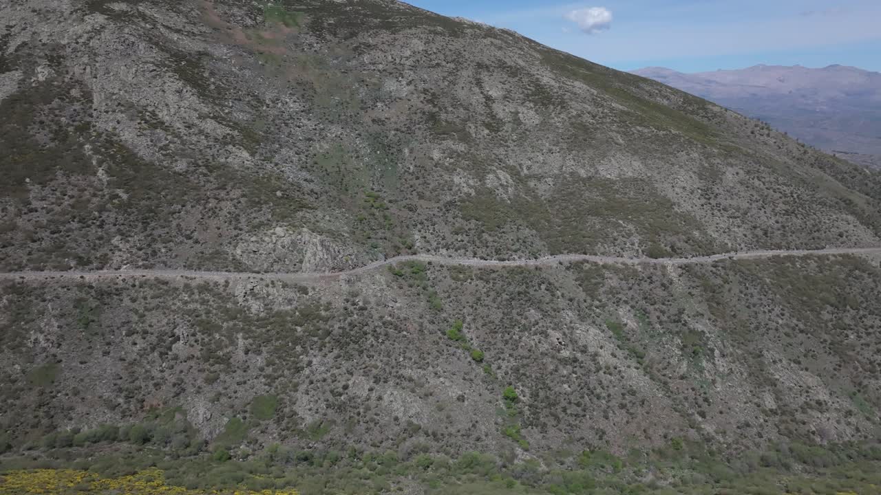 flight with a drone where we see a mountain road and circulating a line formation of bikers we appreciate the great volume of the slope and a valley in the background in Sierra de Gredos Avila Spain
