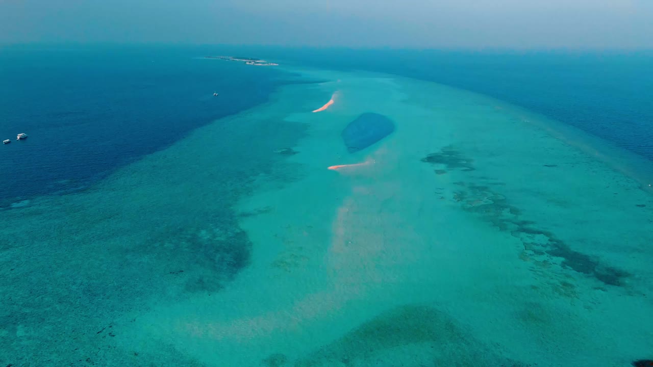 An awe-inspiring aerial drone view captures the Rasdhoo Sandbanks glowing under the soft, golden light of sunset in the Maldives.