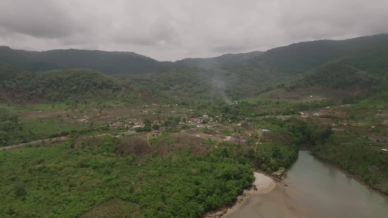 vista aérea del humo que sale de la costa de sierra leona en la base de montañas verdes.