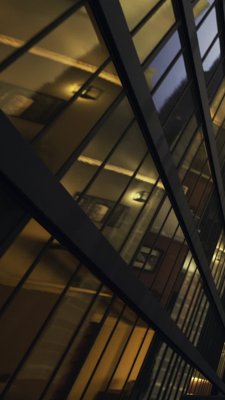 View of a modern building with unique glass design reflecting lights at dusk