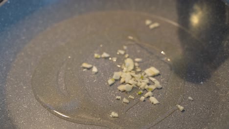 pouring olive oil on a cooking pan with garlic