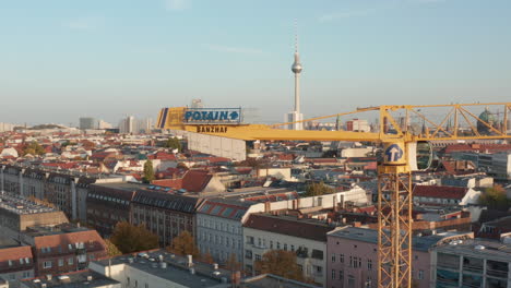 Rising-above-yellow-construction-crane.-Panoramic-view-of-town-landmarks,-Fernsehturm-and-Cathedral.-Berlin,-Germany.