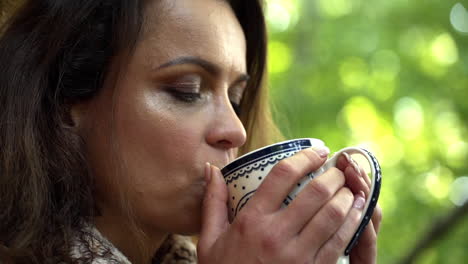 close up fhd shot of a middle-aged woman holding a cup with both hands and enjoying a cup of hot tea for breakfast, slowly opening her eyes