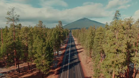 4k-Aerial-country-road-surrounded-by-evergreens-and-mount-in-the-back-Drone-jib-down