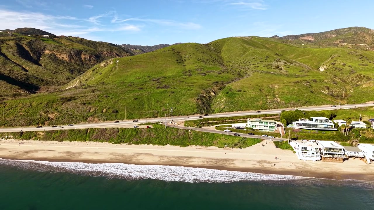 Strandhus ved havet i Malibu fyller rammen i et nært droneopptak, den luksuriøse kysteiendommen avslører arkitektoniske detaljer fra Californias prestisjetunge strandmiljø