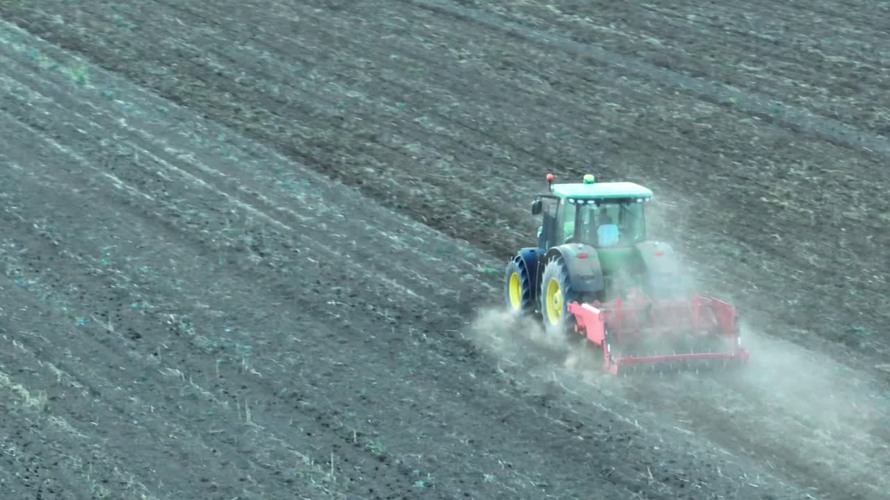 Ripresa con drone di un trattore che ara un campo agricolo di giorno - Polvere che sale nel cielo