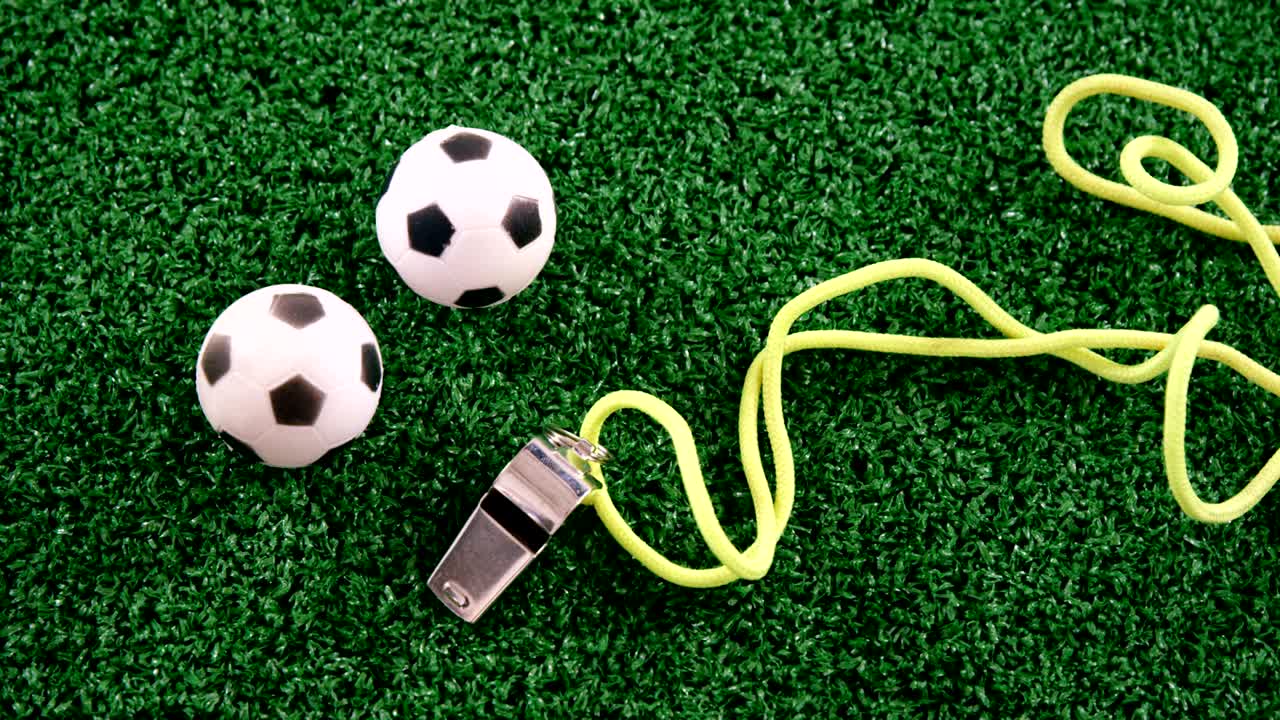 Palloni da calcio e fischietto dell'arbitro su erba sintetica 4k