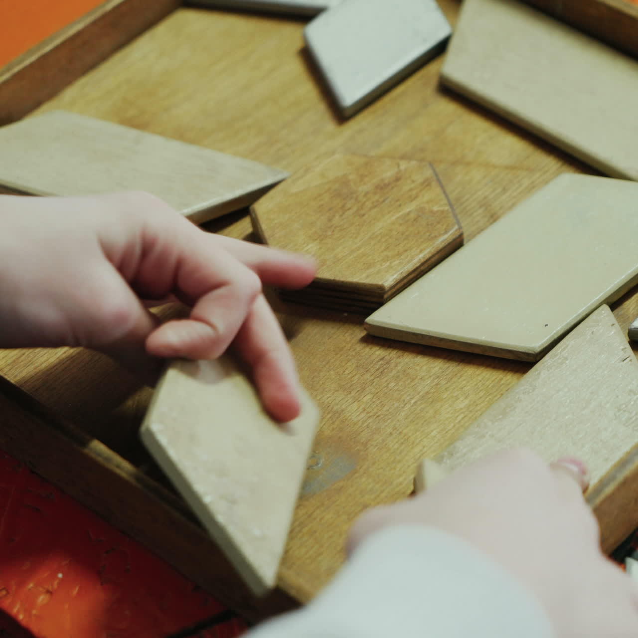 Close-up, hands of a child playing with a wooden puzzle. Concept of education. Square video